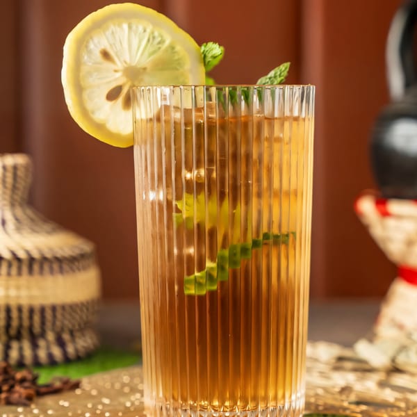 Iced tea with lemon and mint in a ribbed glass, with Ethiopian decor in the background.