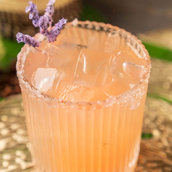 Close-up of a refreshing orange cocktail with ice, garnished with lavender, at Ethiopiques Cafe.