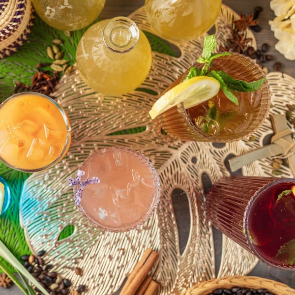Overhead view of various colorful drinks and spices on a decorative placemat.