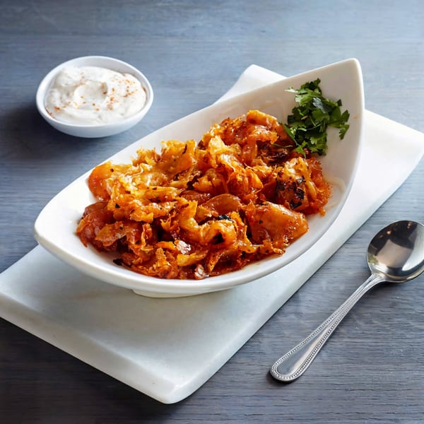 Ethiopian cabbage and potato stew in a white dish with a side of yogurt sauce.