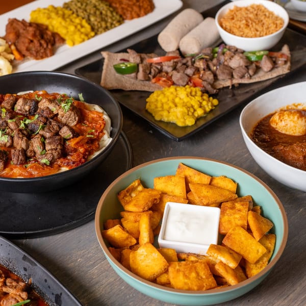 A variety of Ethiopian dishes, including meat stews, injera, and colorful lentil and vegetable sides.